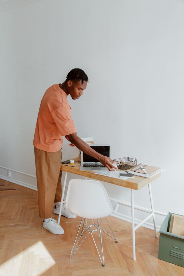 Un homme debout près d’un bureau, rangeant des documents et des appareils électroniques dans un environnement de bureau moderne.